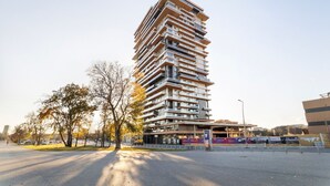 Een modern hoog gebouw met meerdere balkons en een plat dak.