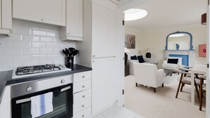 Een moderne keuken met witte kasten, een gasfornuis en een zwart aanrecht.