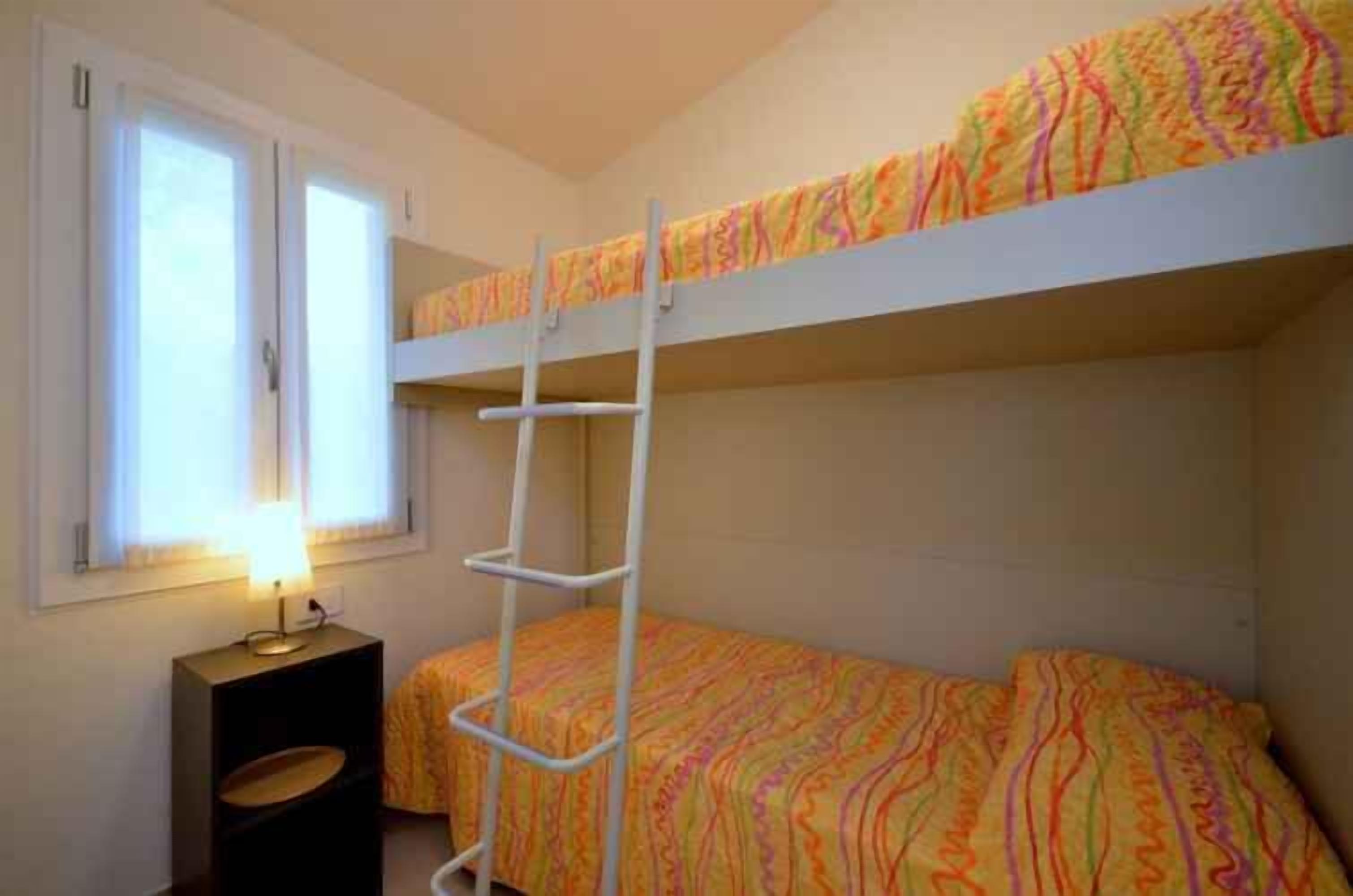 Een slaapkamer met een stapelbed, een nachtkastje en een raam.