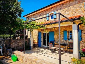 A stone building with a covered patio, outdoor seating, and a pergola. - Holiday home with air conditioning (Krk)
