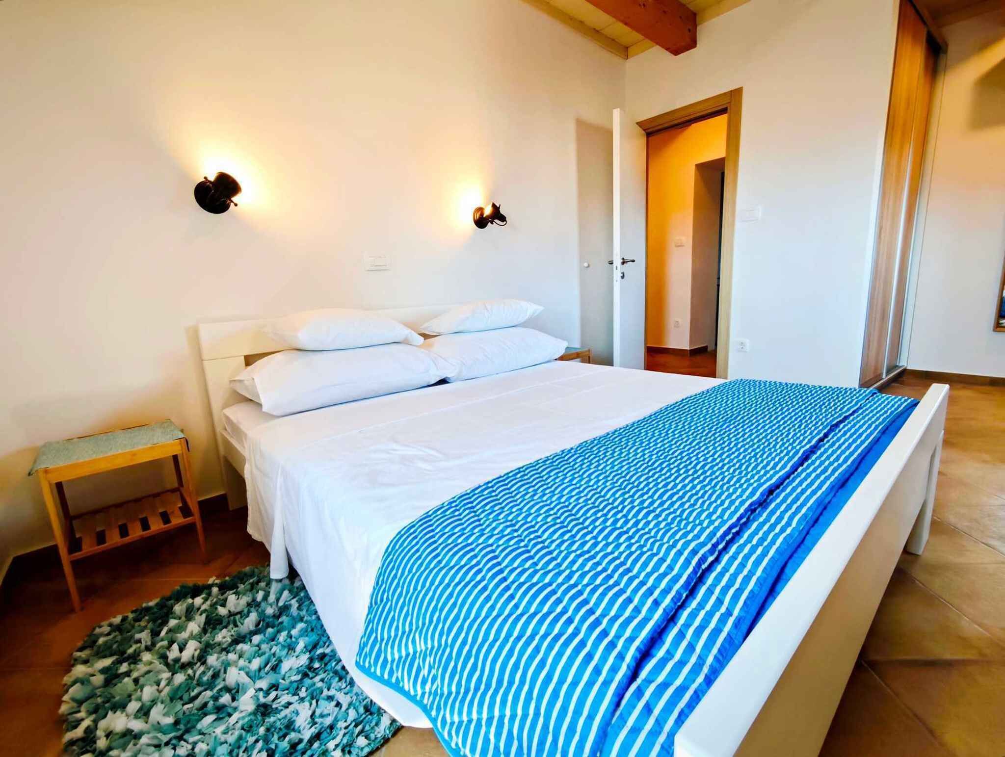 Une chambre à coucher comprenant un lit, une table de chevet, un tapis et deux lampes fixées au mur.