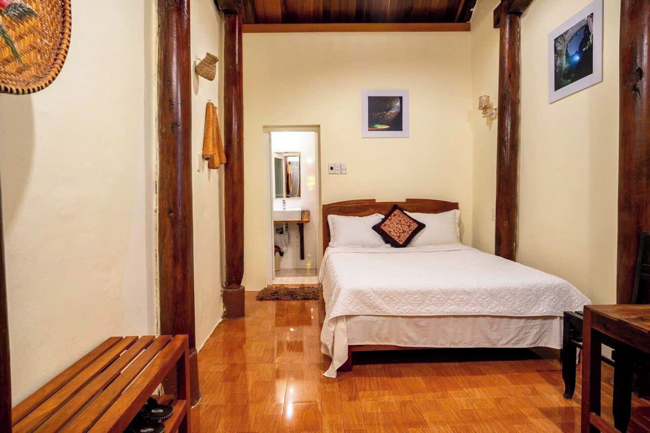 A bedroom with a wooden bed, a bench, and a wooden floor.