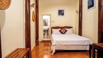 A bedroom with a wooden bed, a bench, and a wooden floor.