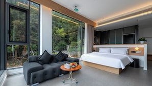 Un dormitorio moderno con una cama grande, un sofá y una pequeña mesa con un florero.