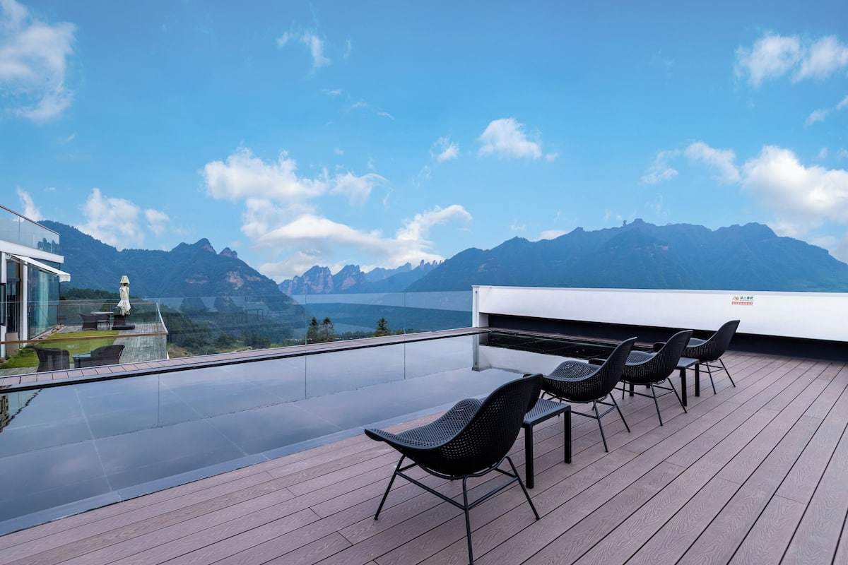 Une terrasse sur le toit dotée d’une balustrade en verre, d’un espace salon extérieur et offrant une vue sur les montagnes.