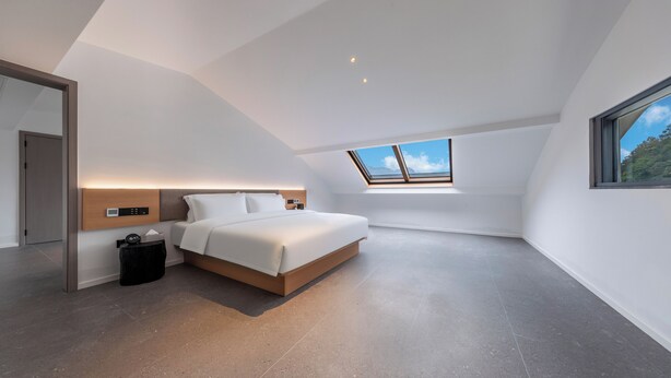 Una camera da letto moderna con un lucernario, un letto, un comodino e un cestino.