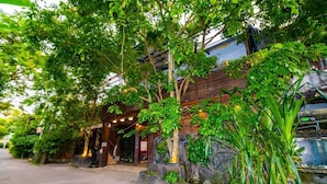 A building with a wooden facade, surrounded by lush greenery and stone planters. - Cinnamon Airport Residences (seeduwa)