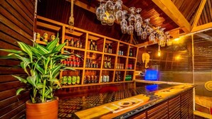 A bar area with shelves of bottles, a potted plant, and a counter with a logo. - Cinnamon Airport Residences (seeduwa)