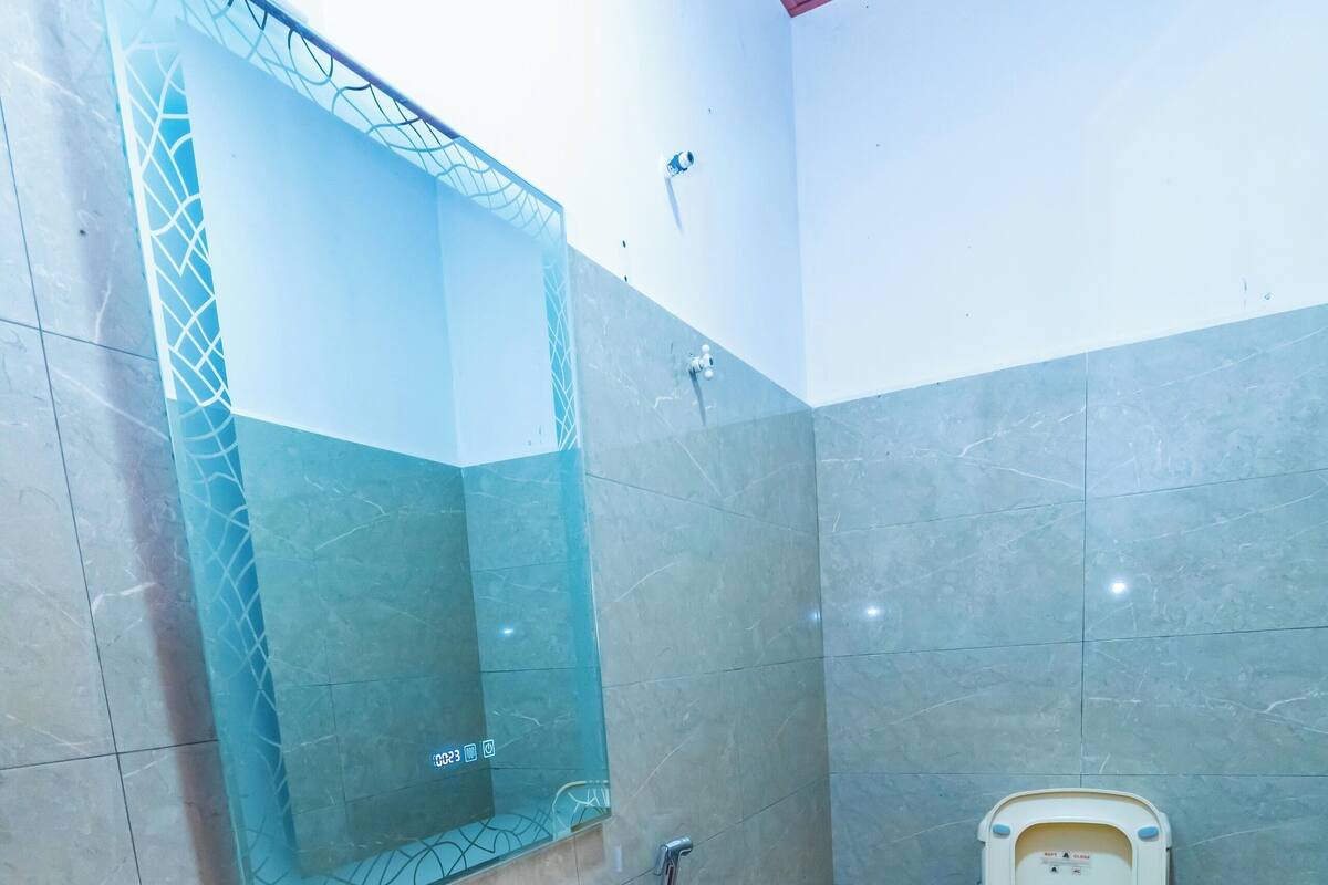 A bathroom with a pedestal sink, a toilet, and a large mirror.