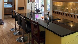 A modern kitchen with a central island, wooden cabinets, and a large window providing natural light. - Cabin at Idabel Family, Pet Friendly with Games Room (Kootenay Boundary E / West Bo*)