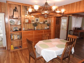 A dining room with a wooden table, chairs, a chandelier, and a bookshelf filled with books and decorative items. - Miners Choice 3 Bedroom on Main St TV WIFI Piano (Julian)