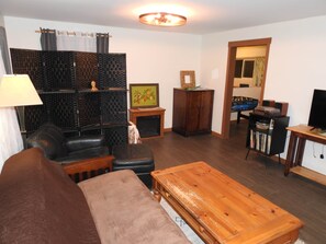 A living room with a sofa, a wooden coffee table, a fireplace, a television, and a bookshelf. - Miners Choice 3 Bedroom on Main St TV WIFI Piano (Julian)