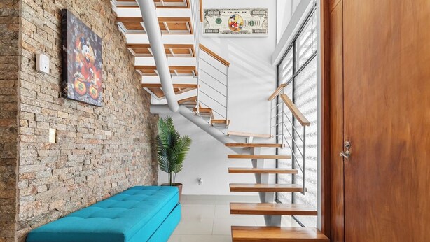 A staircase with wooden steps and metal railings, a blue bench, a brick wall, and a door with a wooden panel. - Seaport | Family Home and Shared Pool (Puerto Vallarta)