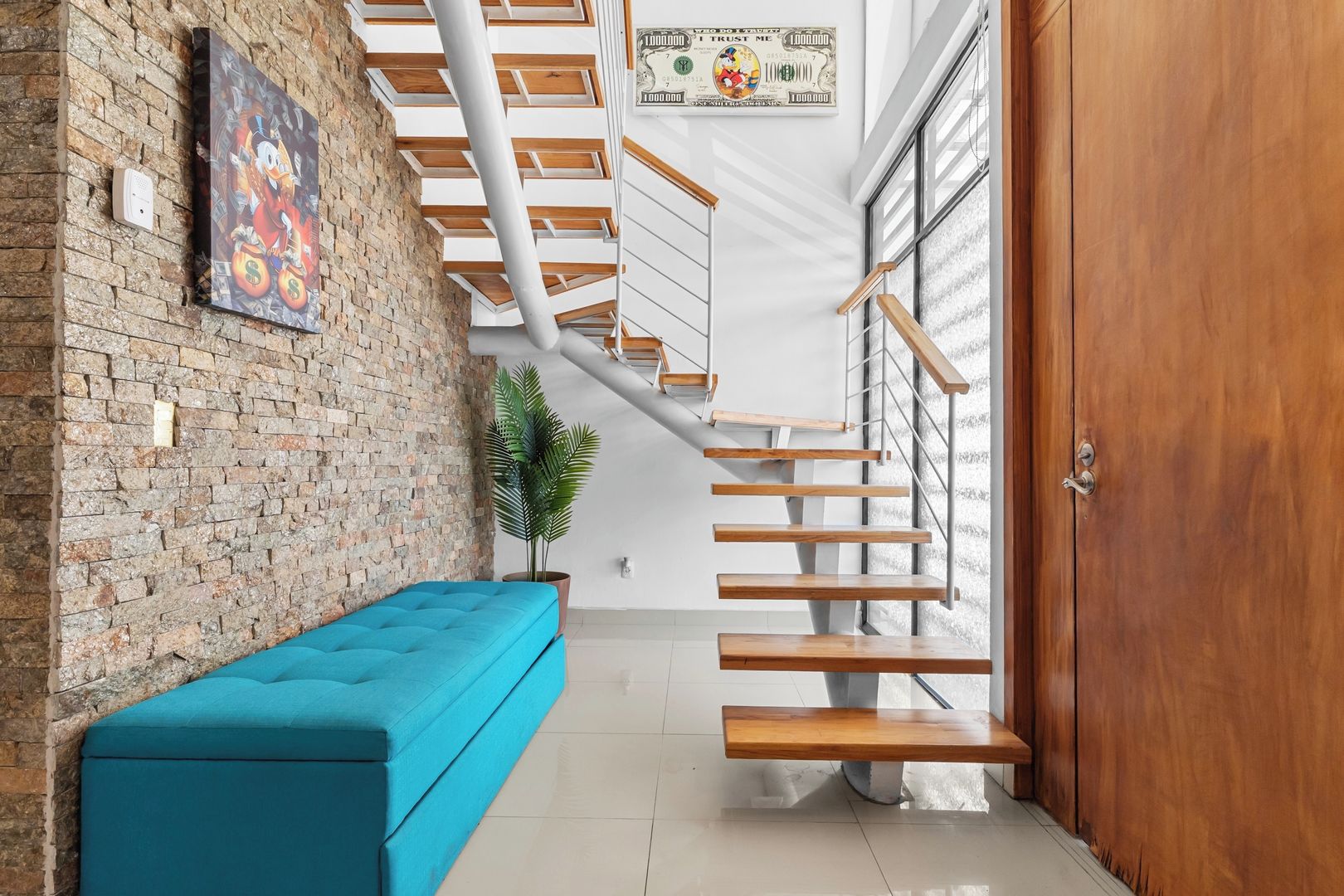 A staircase with wooden steps and metal railings, a blue bench, a brick wall, and a door with a wooden panel.
