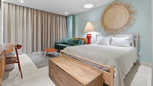 A modern bedroom with a bed, a green sofa, a wooden bench, and a lamp. - Bright studio at Hotel Mio with pool (Bucerías)