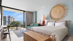 A modern bedroom with a large bed, a desk, and a balcony with a view of buildings. - Bright studio at Hotel Mio with pool (Bucerías)