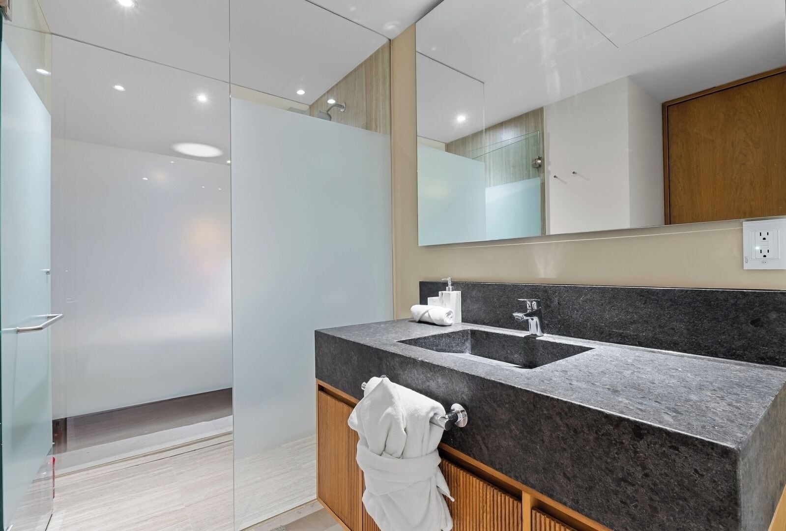 A modern bathroom with a large mirror, a double sink, and a shower area.