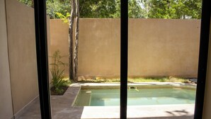 A backyard with a swimming pool, a concrete patio, and a tall fence. - Peregrina Tulum 101A 2BR Luxury Condo (Tulum)