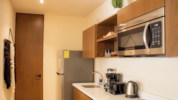 A modern kitchen with a microwave, coffee maker, and kettle on the counter. - Peregrina Tulum 101A 2BR Luxury Condo (Tulum)