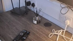 Una mesa de madera con una regleta, un control remoto y un objeto decorativo.