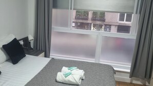Un cuarto de hotel con cama, ventana y vista a la calle.