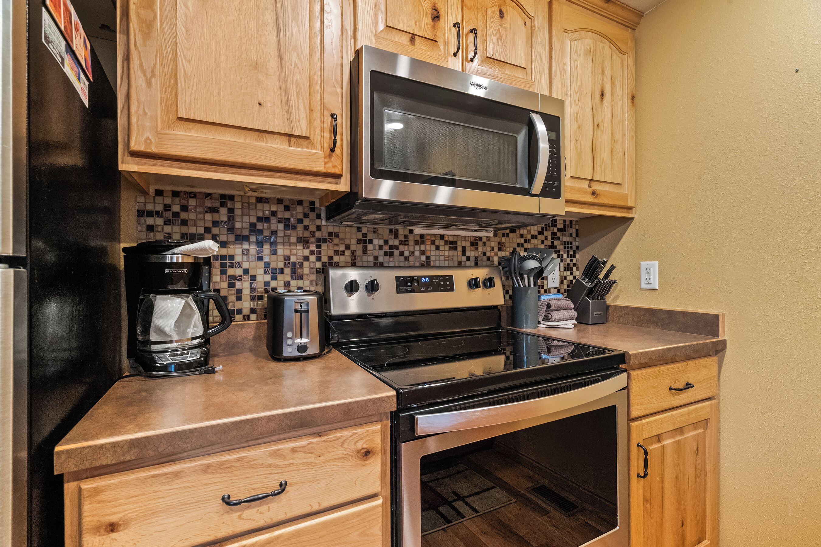 A kitchen with wooden cabinets, a stainless steel microwave, a toaster, and a coffee maker.