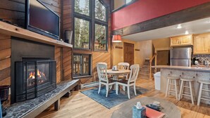 A cozy interior with a fireplace, wooden walls, a dining area, and a kitchen with a refrigerator. - Ski Access SS7B Retreat Pet Friendly  (Brian Head)