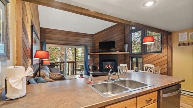 A kitchen with wooden walls, a large island with a sink, and a fireplace. - Ski Access SS7B Retreat Pet Friendly  (Brian Head)