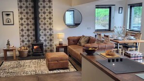 A cozy living room with a fireplace, a sofa, a dining table, and a kitchen area.