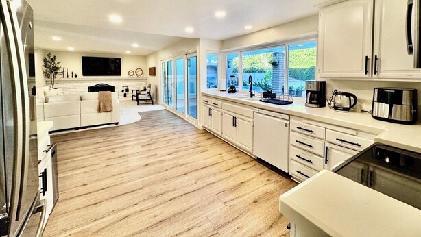 Une cuisine spacieuse dotée d’un plancher en bois, de meubles blancs et d’appareils électroménagers modernes.
