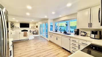 A spacious kitchen with wooden flooring, white cabinetry, and modern appliances.