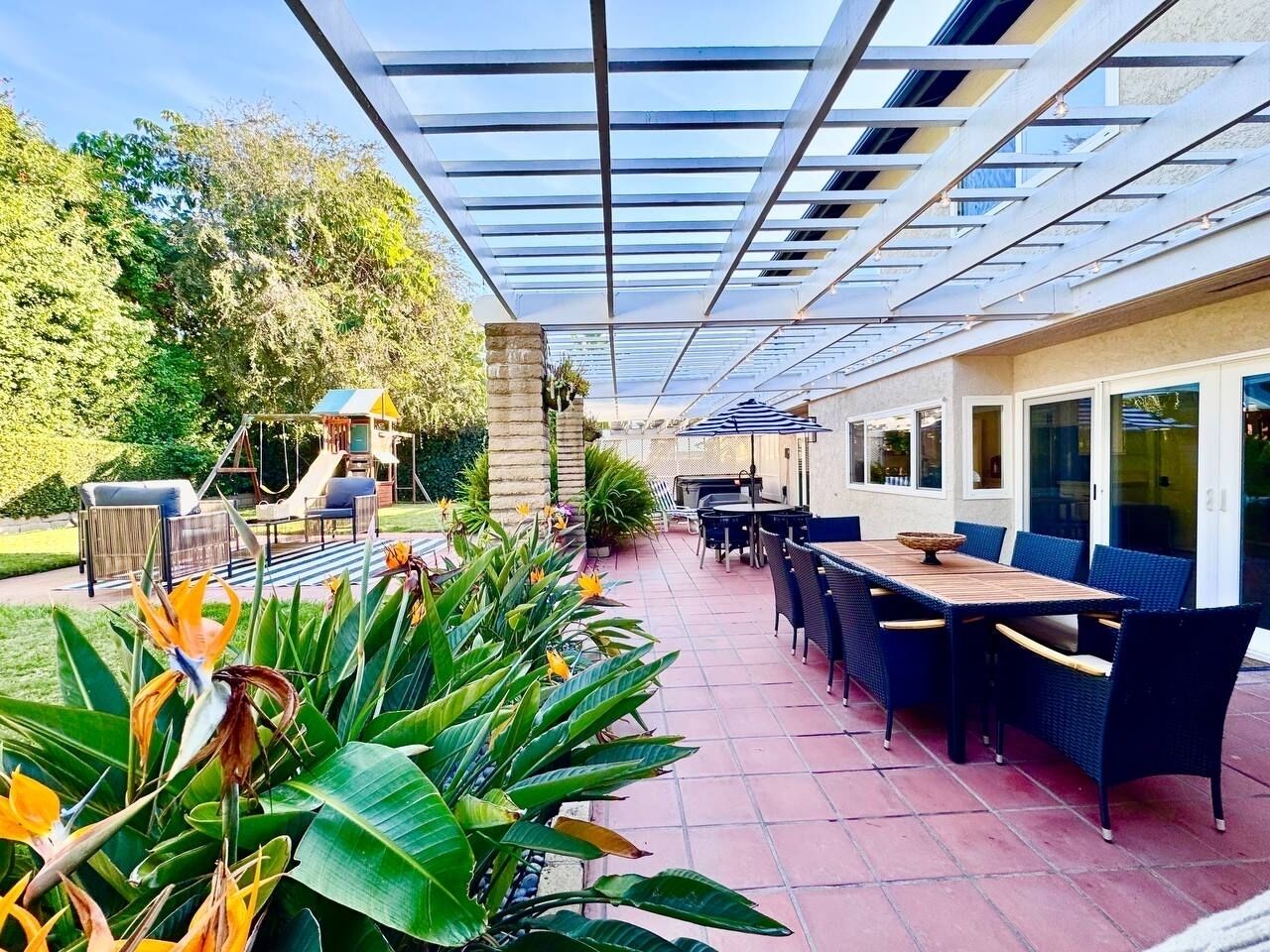 An outdoor patio area with a covered seating area, a play structure, and a dining setup.