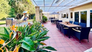 Un espace extérieur aménagé avec une terrasse couverte, une aire de jeux et un coin repas.