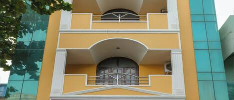 A multi-story building with a yellow facade, a balcony on the second floor, and a sign reading "Maruthi Residency".