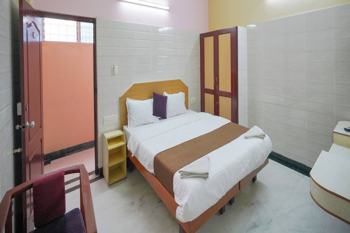 A hotel room with a bed, a wardrobe, a bedside table, and a chair.