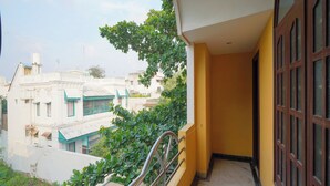A narrow balcony with a metal railing, overlooking a residential area with buildings and greenery. - Maruthi Residency (Puducherry)