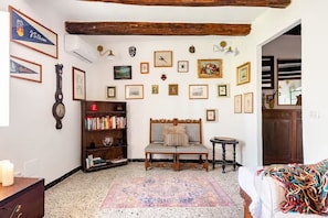 Une pièce avec un plafond en bois, une bibliothèque, un tapis à motifs et divers tableaux encadrés accrochés aux murs.