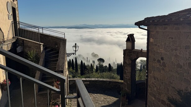 A stone staircase leading to a terrace overlooking a valley with a view of distant mountains and a sea of clouds.