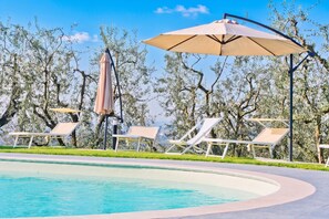 A poolside area with lounge chairs and umbrellas, surrounded by trees. - Great View Dependance Pool & Relax, Lamporecchio, Italy (Lamporecchio)