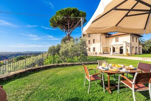 A dining area with a table set for two, overlooking a lush green landscape and a large tree. - Great View Dependance Pool & Relax, Lamporecchio, Italy (Lamporecchio)