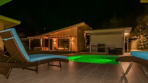 Un espace piscine avec des chaises longues et un patio couvert.