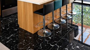 Une cuisine moderne avec des meubles en bois, des appareils en acier inoxydable, un plan de travail en marbre et une grande fenêtre donnant sur un paysage verdoyant.
