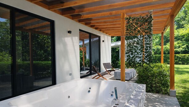 Un espace moderne aménagé à l’extérieur avec un jacuzzi, une pergola, des sièges et une vue sur le jardin.