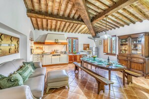 A spacious living area with a dining table set for six, a sofa with patterned cushions, and a kitchen in the background. - Berignone Natural Paradise Apt with Pool, Volterra, Italy (Volterra)