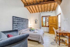 A bedroom with a bed, a chair, a desk, a wooden ceiling, and a window. - Berignone Natural Paradise Apt with Pool, Volterra, Italy (Volterra)