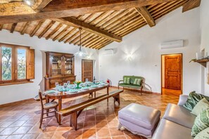 A dining area with a wooden table set for four, a bench, and a sofa. - Berignone Natural Paradise Apt with Pool, Volterra, Italy (Volterra)
