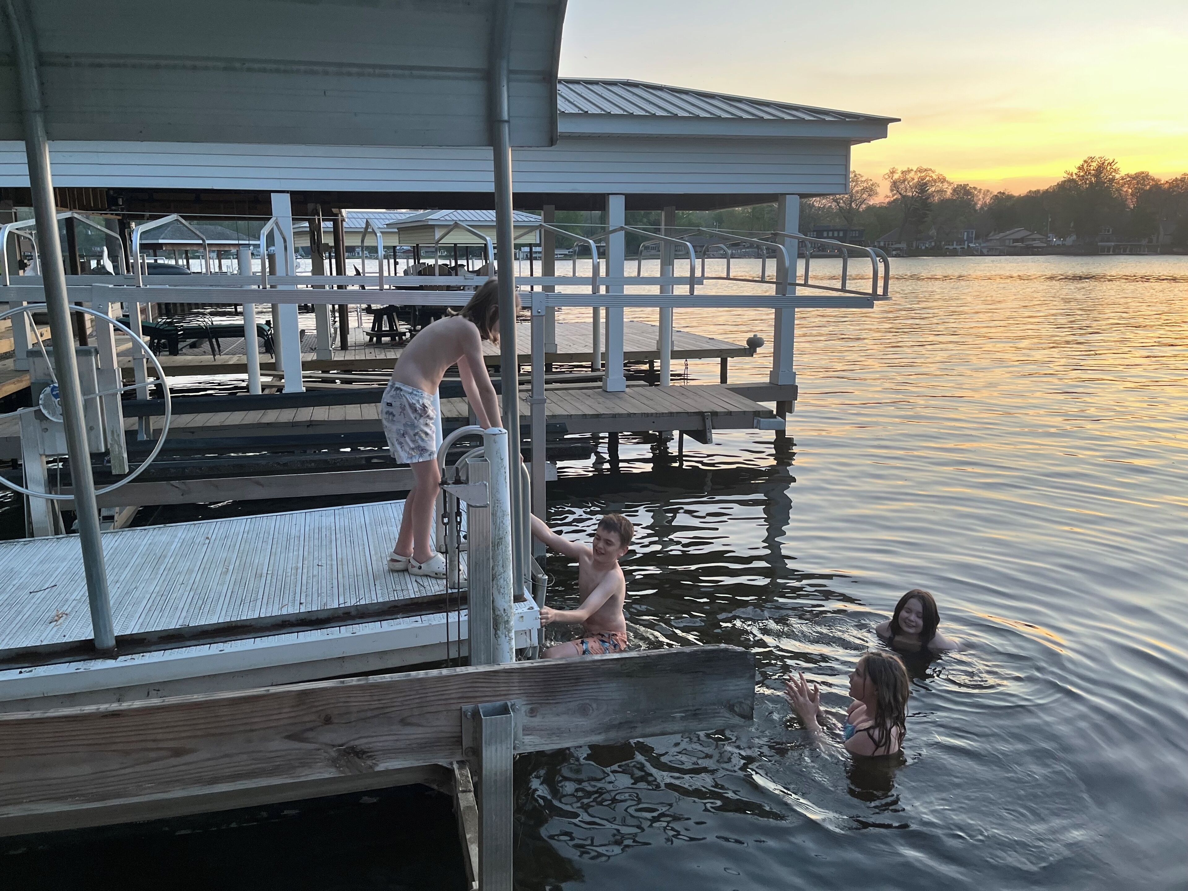A pier with a covered seating area, a dock, and a calm body of water.