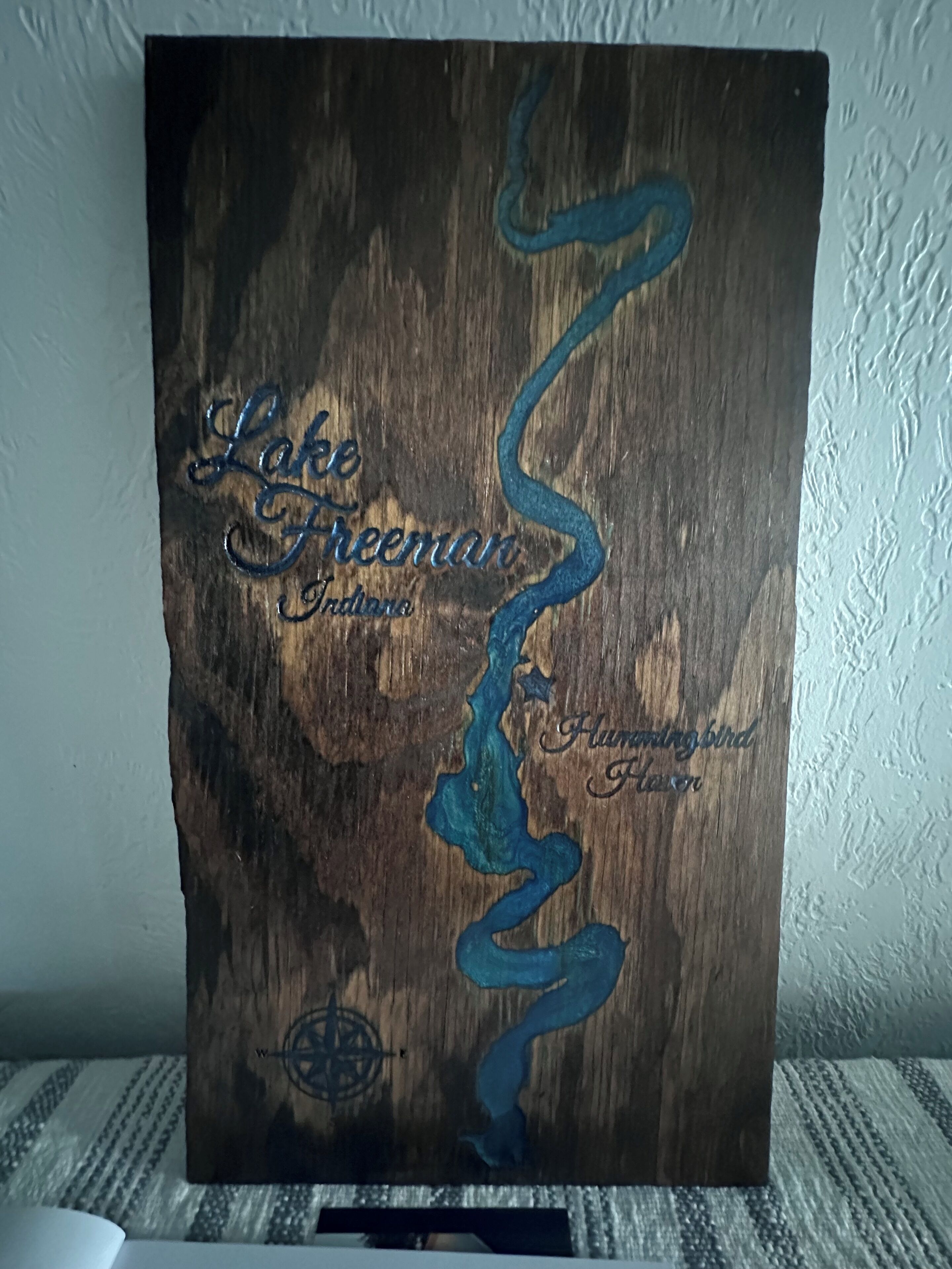 Una obra de arte de madera con texto y una brújula.