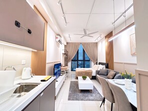 Ein modernes Hotelzimmer mit einer Küchenzeile, einem Bett mit Blick auf die Stadt, einem Schreibtisch mit Stuhl und einem Essbereich.
