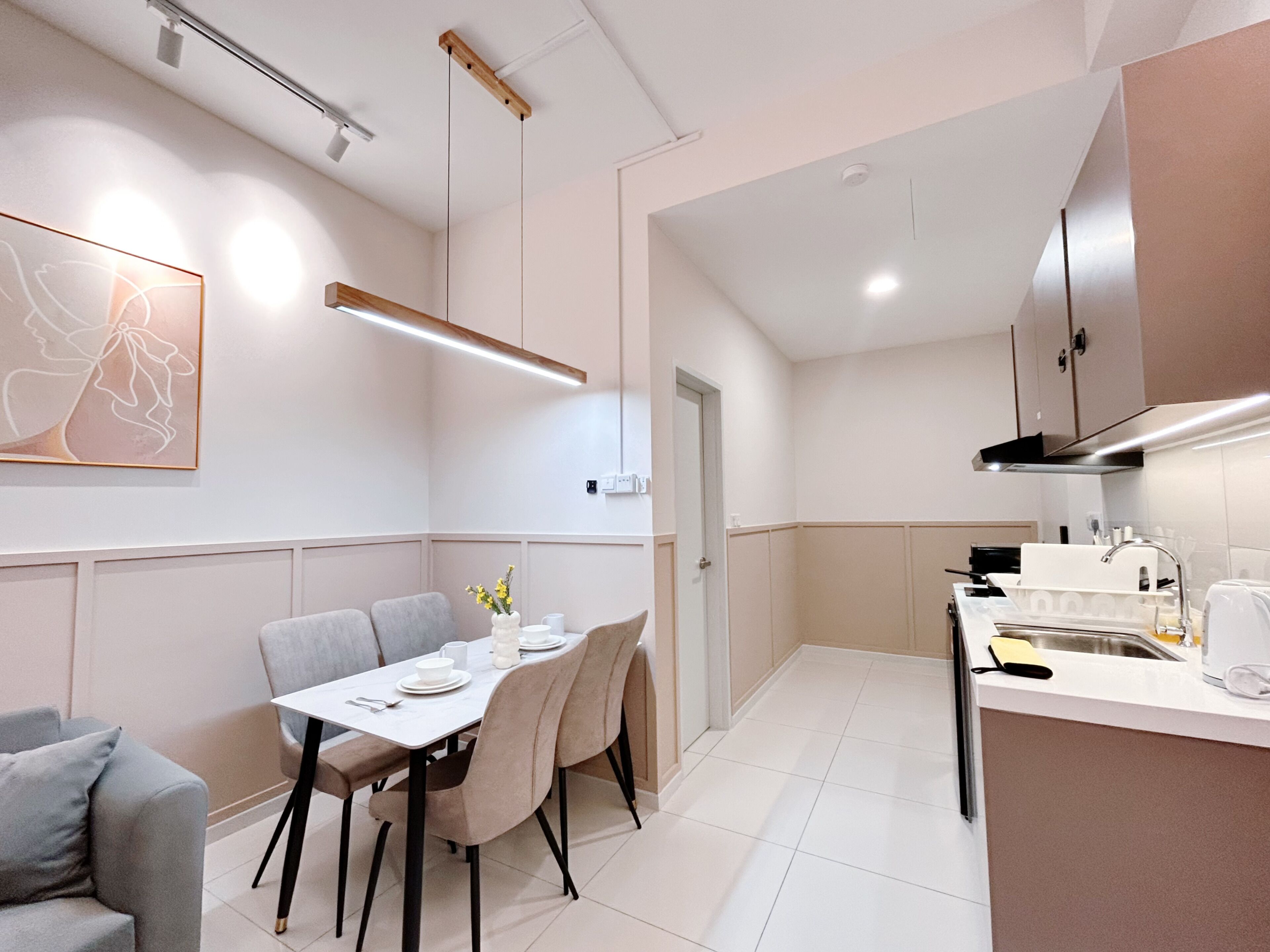 Una cocina moderna con armarios blancos, un comedor con mesa y sillas, y una isla de cocina con pileta y encimera.